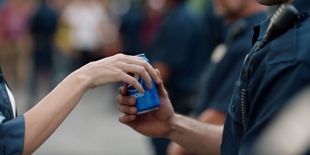 Eine Hand reicht ener andeen eine Dose Pepsi-Cola