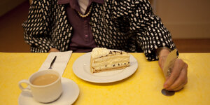 Demenzkranke Frau im Pflegeheim vor ihr steht ein Stück Kuchen und eine Tasse Kaffee