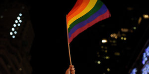 Eine LGBT-Fahne weht vor dunklem Nachthimmel