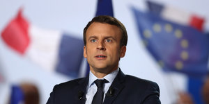 Emmanuel Macron steht vor der französischen und der europäischen Flagge