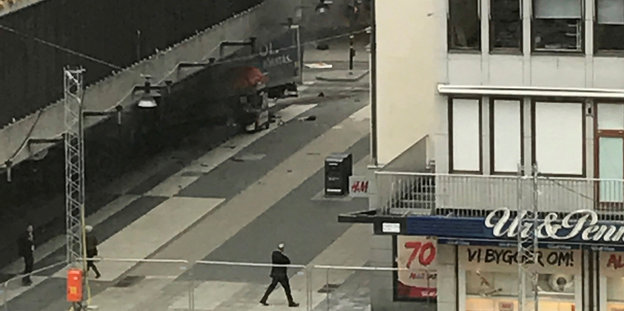 Die Rückseite eines Lastwagens ragt aus einer Kaufhausfassade, Rauch steigt auf