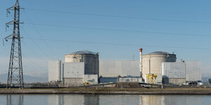 Vor strahlend blauem Himmel steht das Atomkraftwerk Fessenheim und spiegelt sich im Wasser