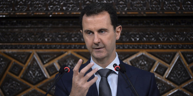 Syriens Diktator Baschar Assad hebt beim Sprechen predigend eine Hand