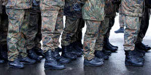 Eine Reihe von Beinen in Tarnhosen und Militärstiefeln