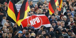 Ausschnitt einer Pegida-Demo: Demonstranten schwenken Deutschland-Flaggen und ein NPD-Banner
