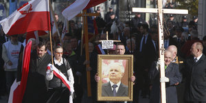 Menschen mit katholischen kreuzen und polnischen Flaggen