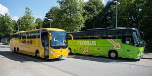 Ein grüner Flixbus überholt einen gelben Postbus