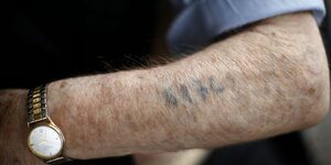 Ein Holocaust-Überlebender zeigt seinen Arm mit der tätowierten Nummer