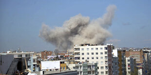 Eine graue Rauchwolke steigt über dem hellblauen Himmel über Diyarbakir auf