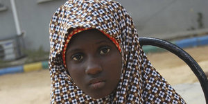 Ein Mädchen mit rot-weißem Kopftuch aus Nigeria