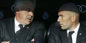 Ancelotti und Zidane in schwarzen Anzügen im Halbschatten sitzend
