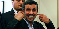 Ahmadinedschad lacht spitzbübisch und deutet mit den Zeigefingern auf seine Ohren