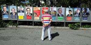 Ein Mann schaut auf viele Wahlplakate