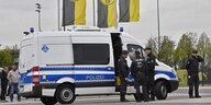 Polizisten stehen uniformiert vor einem Einsatzwagen, dahinter BVB-Logos