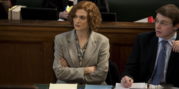 Rachel Weisz sitzt mit verschränkten Armen neben einem Kollegen im Gericht