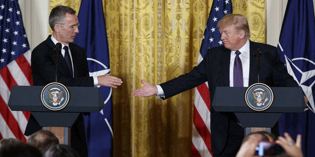 Jens Stoltenbergund Donald Trump stehen jeweils hinter einem Podium und setzen zum Handschlag an