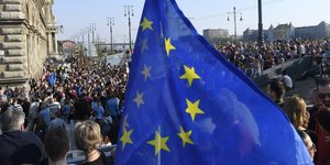 Hunderte Menschen stehen hinter einer Flagge der EU