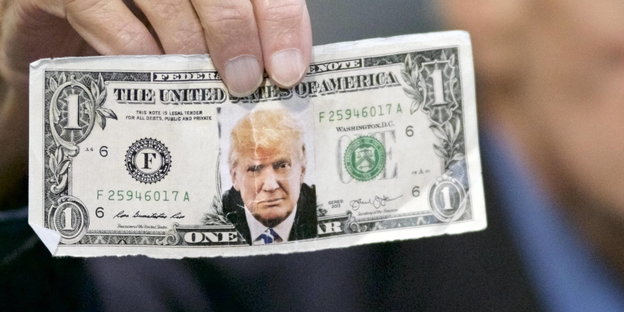 Trump-Unterstützer Jerry Lambert hält einen Dollarschein mit einem Bild von Donald Trump in die Kamera