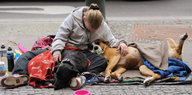 Eine Frau sitzt mit ihrem Hund auf der Straße