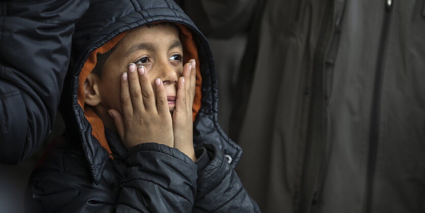 Ein kleiner Junge mit vors Gesicht geschlagenen Händen