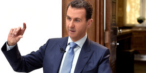 Baschar al-Assad in Anzug und mit erhobenem Finger