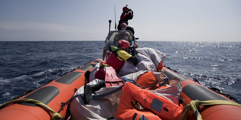 Retter in einem Schlauchboot suchen mit Ferngläsern das Meer ab