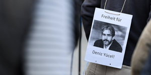 Ein Mann hat sich während einer Mahnwache vor der Stadthalle in Flörsheim (Hessen) ein Transparent mit der Aufschrift "Freiheit für Deniz Yücel !" umgehängt.