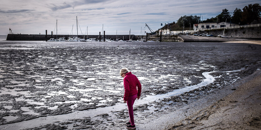 Eine Frau steht an einem Strand bei Ebbe