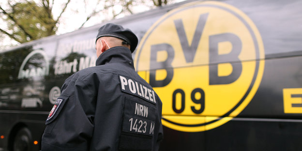 Polizist in Rückansicht vor dem Mannschaftsbus des BVB