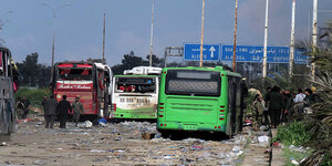 Drei stark zerstörte Busse an einer Autobahn, im Hintergrund blaue Ausfahrtschilder