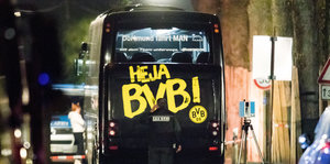Ein Mann mit LKA-Jacke steht vor dem schwarz-gelben BVB-Mannschaftsbus