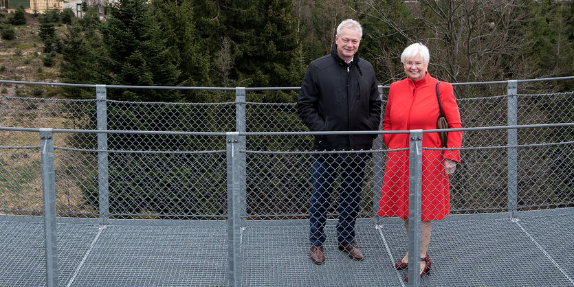 Eine Frau und ein Mann auf einer Brücke - im Hintergrund Büume und Wiese