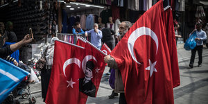 Ein Händler trägt türkische Fahnen, die über seinen Körper hängen