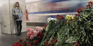 Eine junge Frau steht vor einem Berg mit Blumen in einer Metro-Station