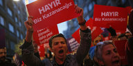 Ein junger Mann inmitten von DemonstrantInnen hält ein Schild mit dem türkischen "Nein" in die Höhe