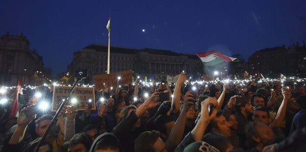 Eine Menschenmenge hält nachts ihre leuchtenden Smartphones in die Luft
