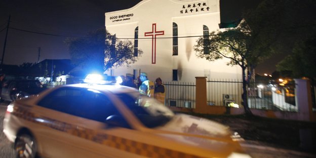Eine Kirche vor der ein Polizeiauto steht