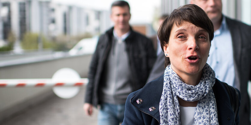 Eine Frau mit kurzen Haaren und Schal scheint gerade zu sprechen