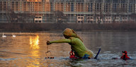 Menschen schwimmen mit einer Justizia-Figur durch einen Fluss