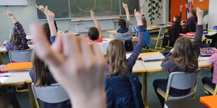 Schülerinnen und Schüler melden sich in einem Klassenraum