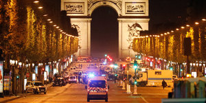 Ein Krankenwagen fährt auf Arc de Triomphe zu. Die hell erleuchtete Straße