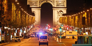 Ein Krankenwagen fährt auf Arc de Triomphe zu. Die hell erleuchtete Straße