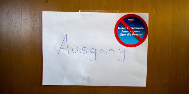 An einer Tür hängt ein Zettel mit der Aufschrift „Ausgang“ und einem AfD-Aufkleber „Nein zu Schmutzkampangnen über die Presse“