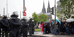 Polizisten und Demonstranten stehen sich gegenüber, im HIntergrund der Kölner Dom