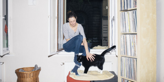 Sarah Kuhnt sitzt auf ihrer Fensterbank und streichelt eine Katze
