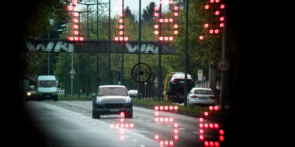 Durch den Sucher einer Laserpistole sind fahrende Autos zu sehen. Ihre Geschwindigkeit wird in roten Digitalziffern angezeigt