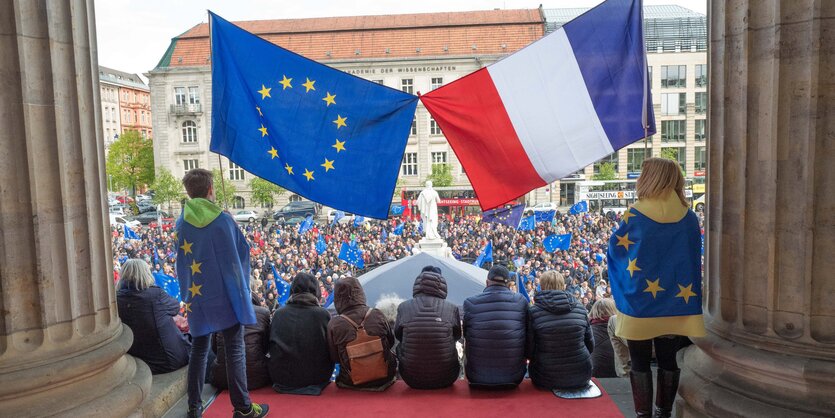 Demonstranten sitzen bei der "Pulse of Europe"-Kundgebung auf den Stufen des Konzerthauses am Gendarmenmarkt in Berlin unter einer EU- und einer französischen Flagge