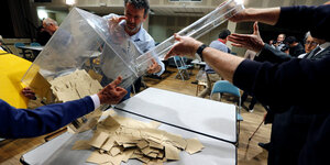 Menschen schütten Wahlurnen auf einen Tisch aus