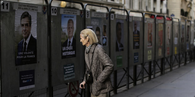 Eine Frau guckt sich Wahlplakate an