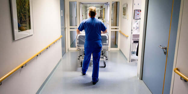 Krankenpfleger schiebt Bett durch Flur
